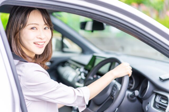 車の運転席から笑顔で振り返る女性