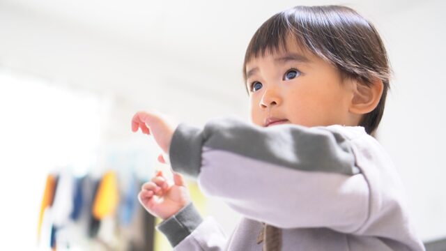 何かを指さして興味を示す小さな子供